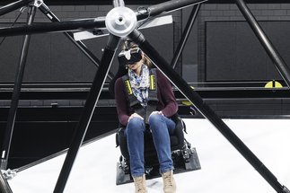 Person mit VR-Brille sitzt auf CableRobot-Simulator