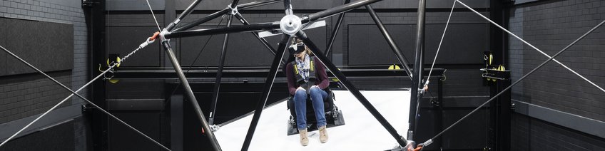 Bewegungswahrnehmung & Simulation Person mit VR-Brille sitzt auf CableRobot-Simulator